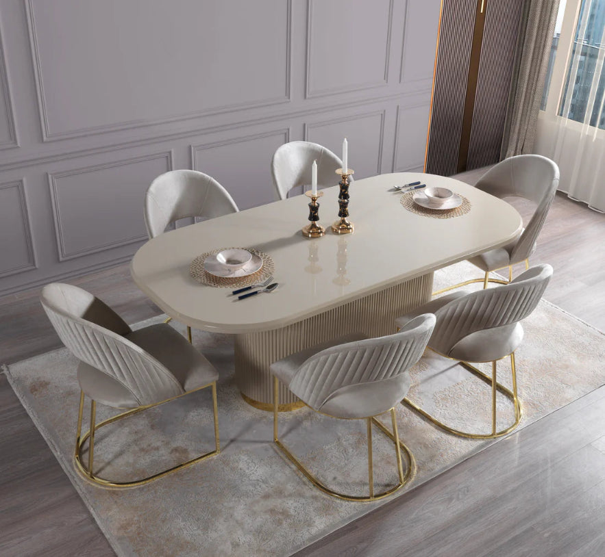 A 7-piece dining set featuring a round beige table with gold legs and a white finish, accompanied by seven chairs with gold legs and white upholstery.